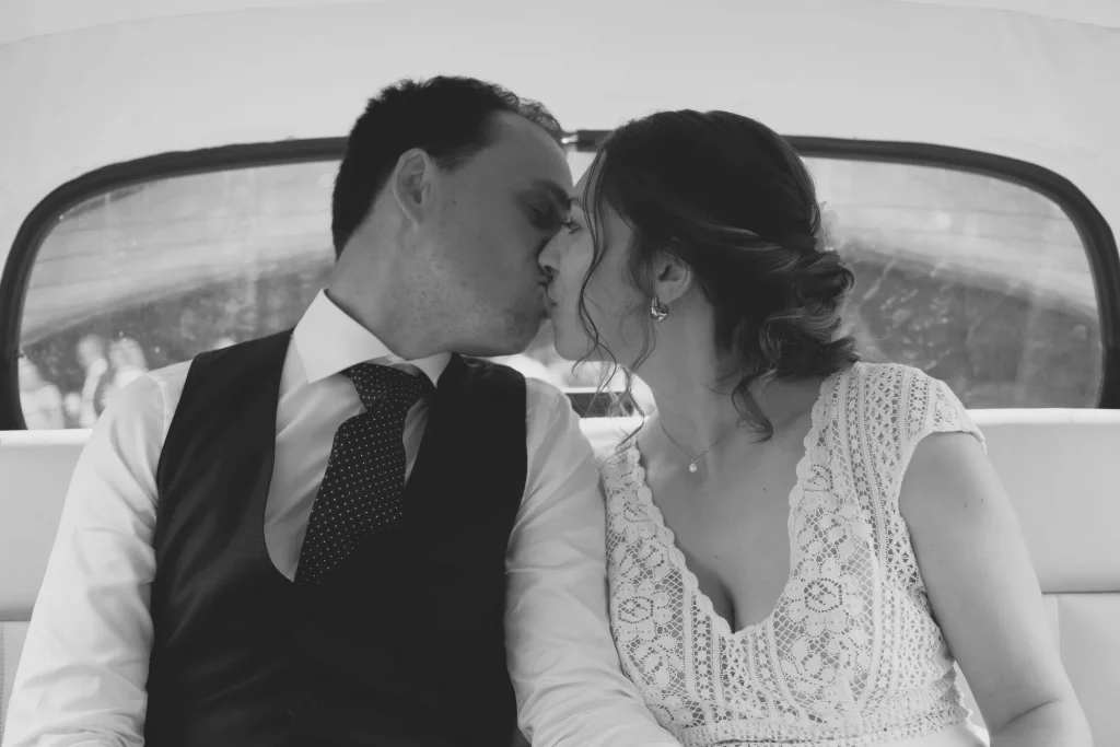 Baiser de mariés dans une voiture vintage à Saint-Hilaire-du-Harcouët en Normandie.