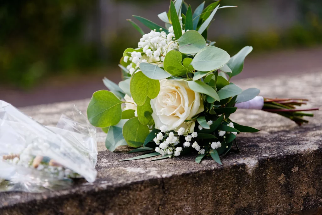 Bouquet de mariée avec rose blanche et eucalyptus sur un muret à Saint-Hilaire-du-Harcouët.