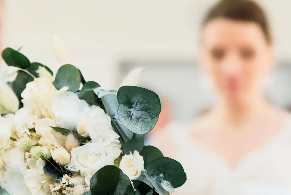 Bouquet de mariée roses blanches et eucalyptus, flou artistique en arrière-plan en Normandie.