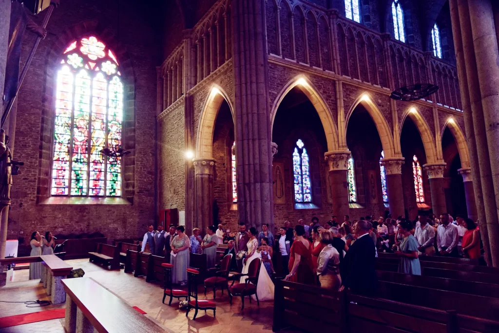 Cérémonie de mariage à l'église de Saint-Hilaire-du-Harcouët en Normandie, mariés devant les vitraux.