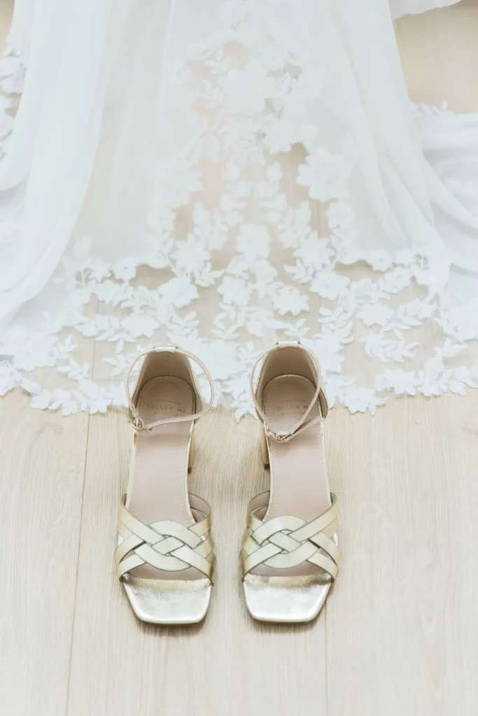 Chaussures de mariée dorées devant une robe en dentelle à Saint-Hilaire-du-Harcouët, Normandie.