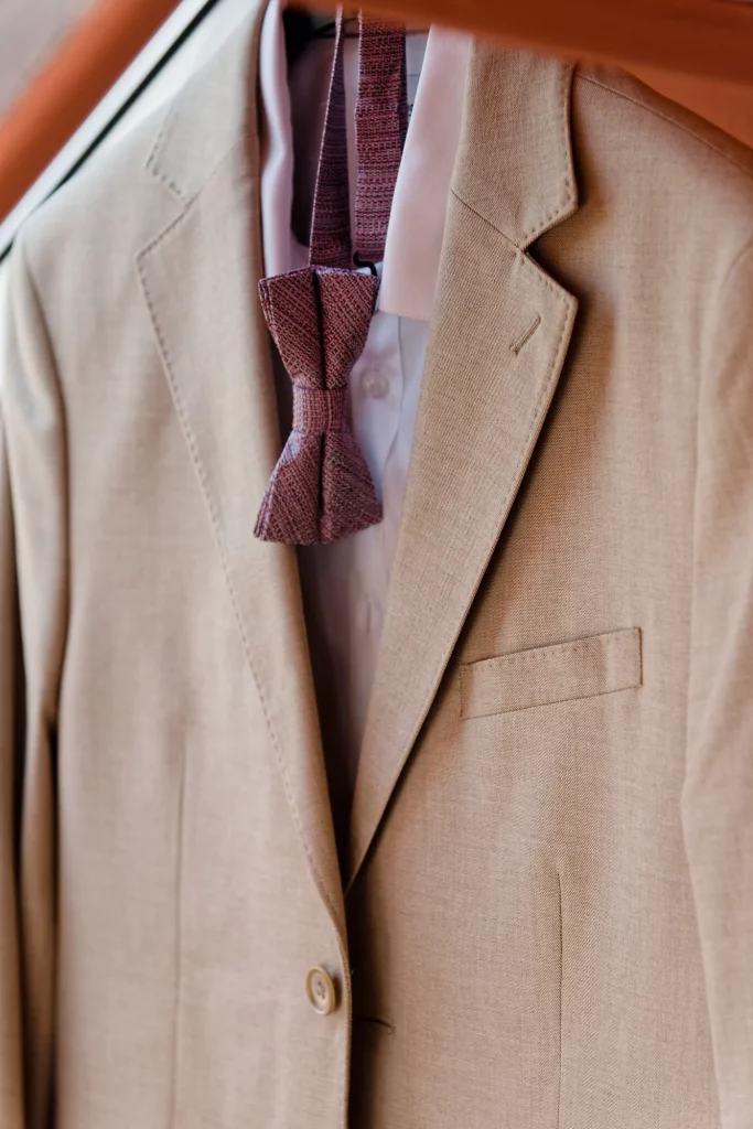 Costume de marié beige et nœud papillon bordeaux suspendus à Saint-Hilaire-du-Harcouët, Normandie.