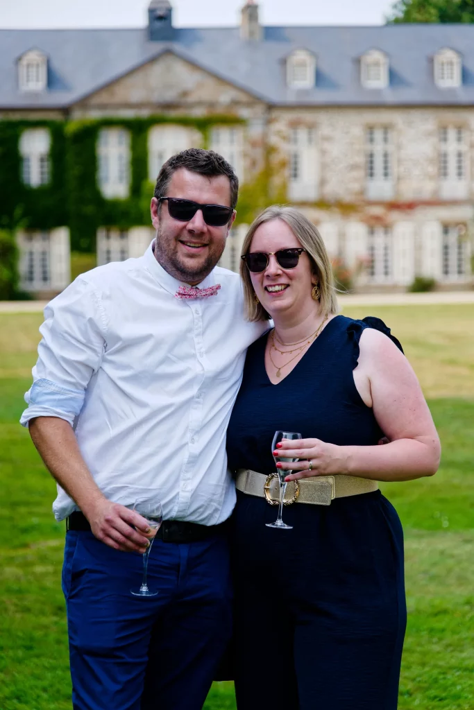 Couple avec champagne devant un manoir en Normandie pour un mariage à Saint-Hilaire-du-Harcouët.