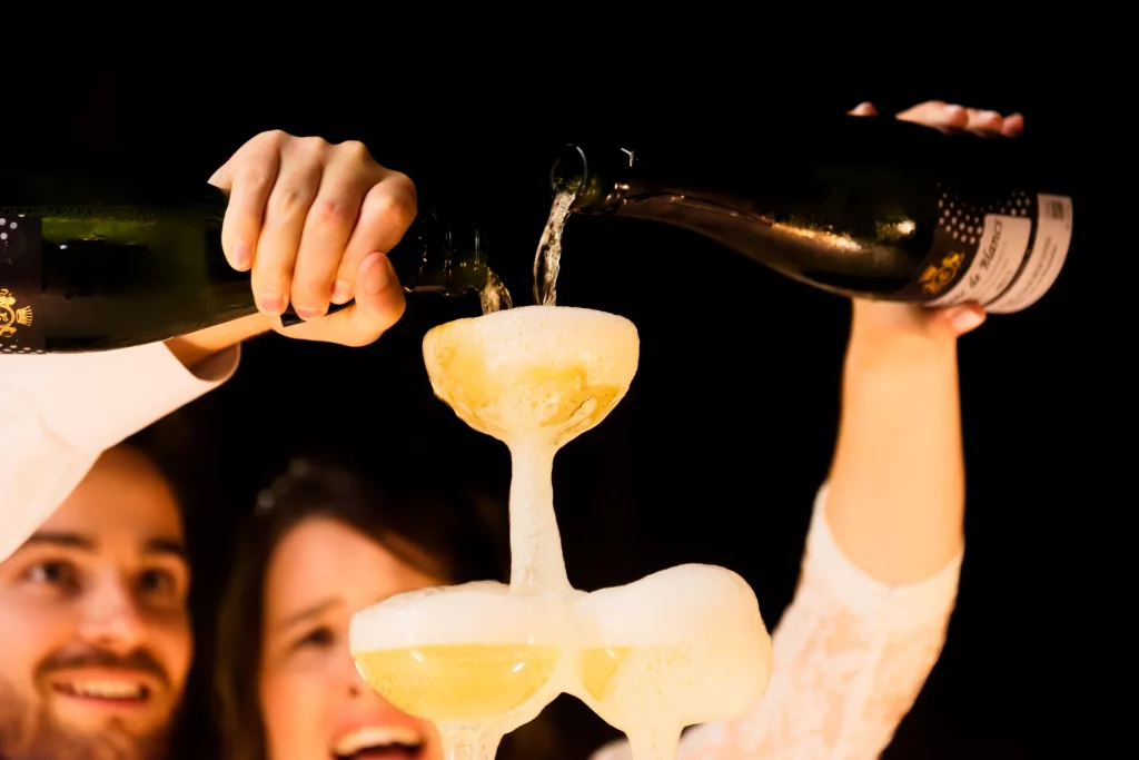 Couple versant du champagne sur une pyramide de coupes lors d'un mariage en Normandie.