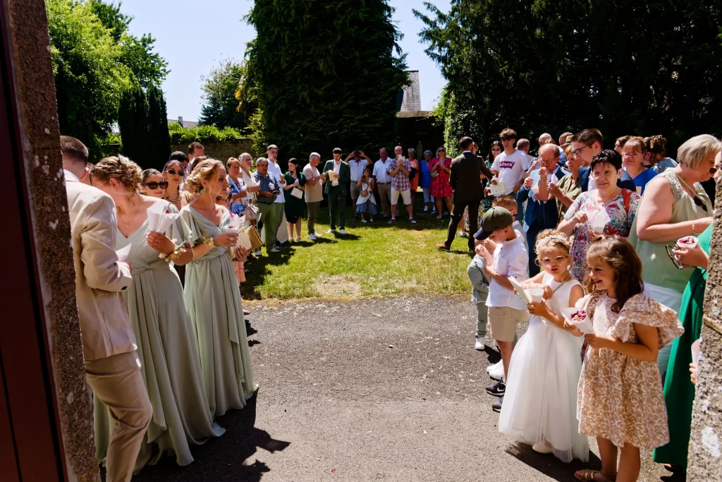 Demoiselles d'honneur en vert sauge et enfants à la sortie d'un mariage à Saint-Hilaire-du-Harcouët en Normandie.