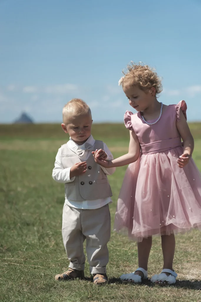 Enfants d'honneur en tenue de fête devant le Mont Saint-Michel en Normandie, style documentaire.