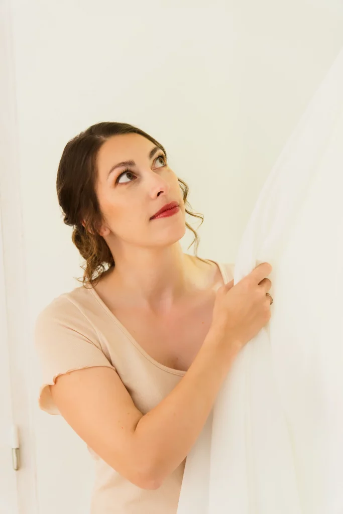 Future mariée émue regardant vers le haut en tenant son voile à Saint-Hilaire-du-Harcouët, Normandie.