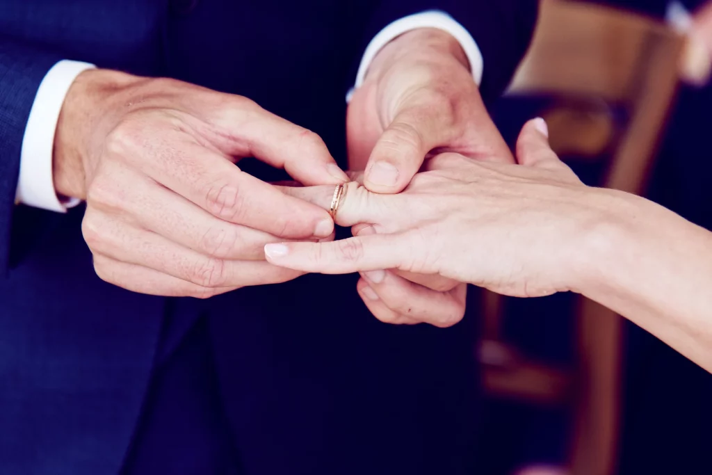 Gros plan d'un marié passant l'alliance au doigt de sa femme lors d'un mariage en Normandie.