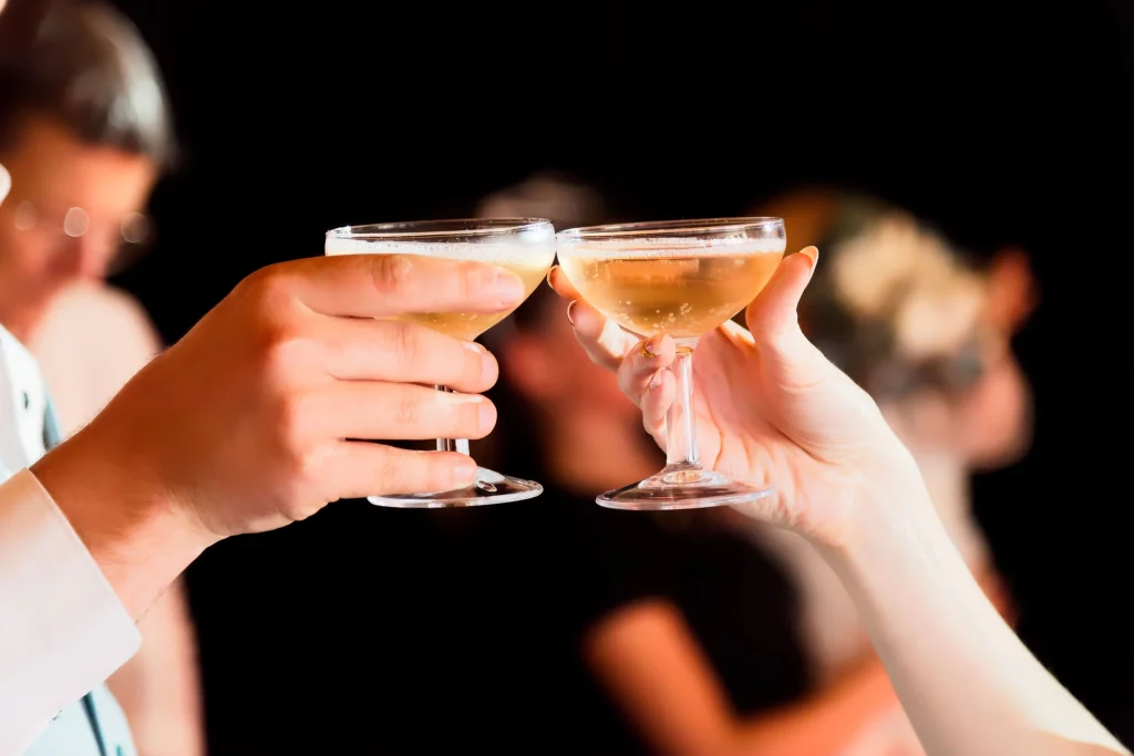 Gros plan de deux mains trinquant avec des coupes de champagne lors d'un mariage en Normandie.