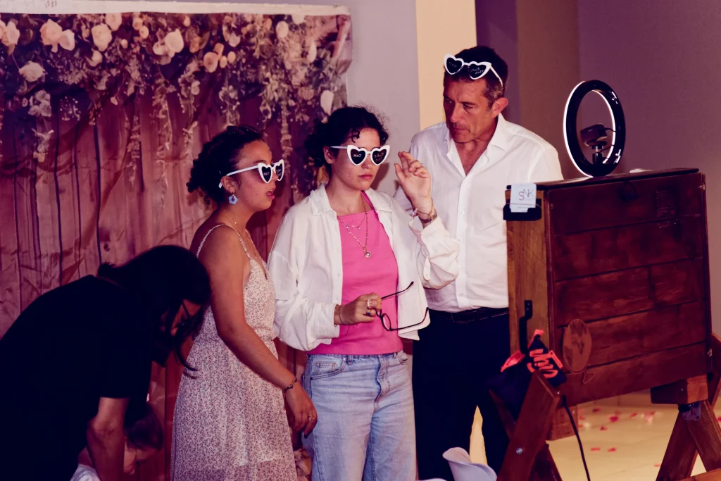 Invités avec lunettes cœur devant une borne photo, mariage à Saint-Hilaire-du-Harcouët, Normandie.