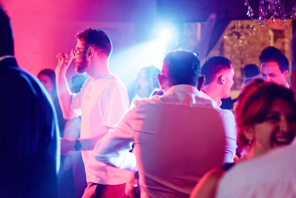 Invités dansent à un mariage en Normandie sous des projecteurs roses et bleus à Saint-Hilaire-du-Harcouët.