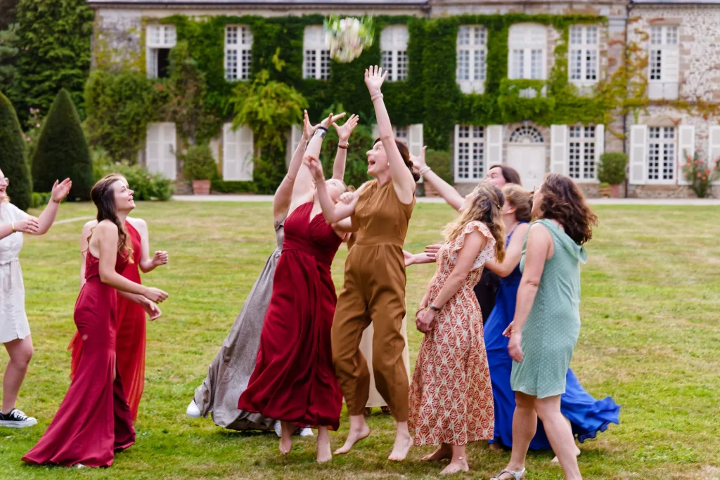 Lancer de bouquet devant un château en Normandie, invitées sautant avec joie.