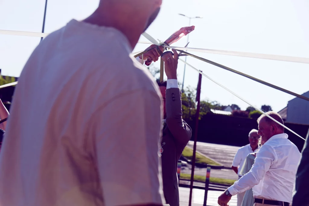 Marié coupant un ruban au ciseau lors d'une cérémonie à Saint-Hilaire-du-Harcouët en Normandie.