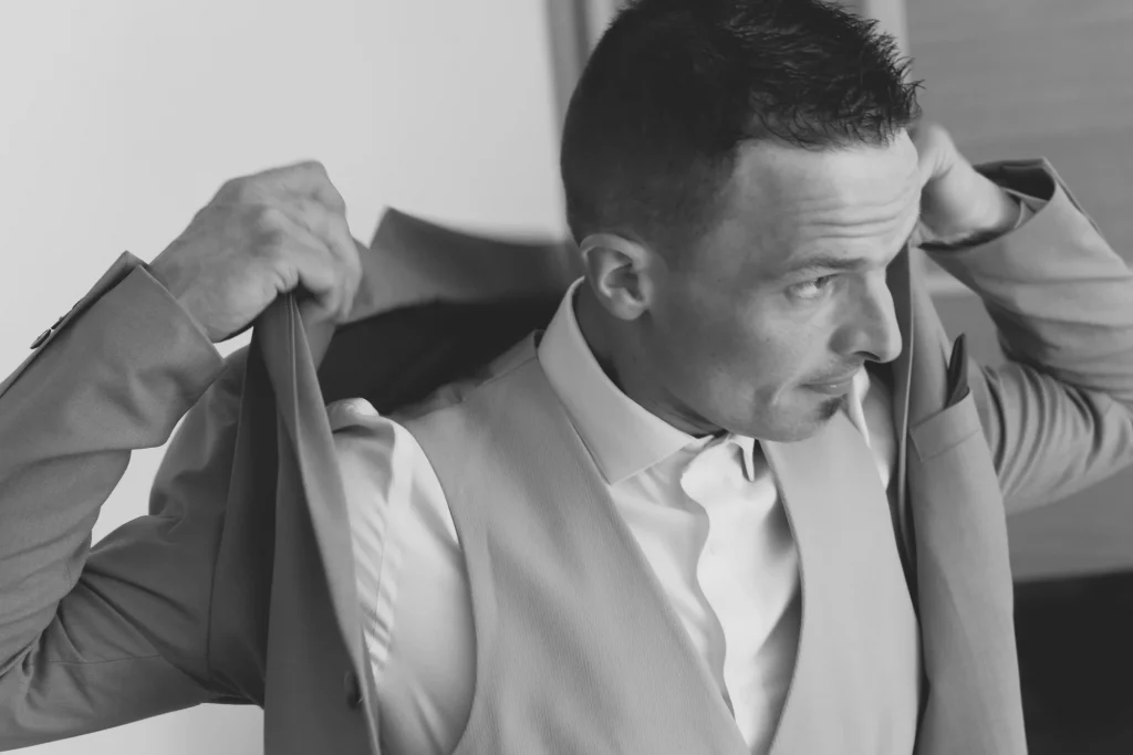 Marié enfilant sa veste de costume à Saint-Hilaire-du-Harcouët en Normandie, photo noir et blanc.