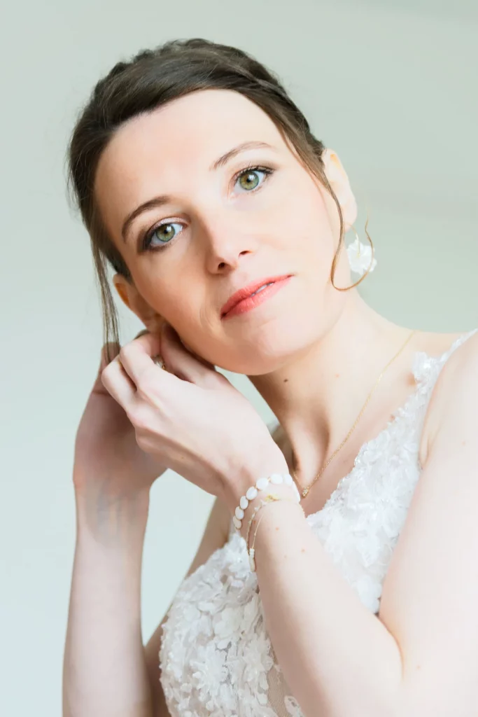 Mariée en Normandie ajustant ses boucles d'oreilles avant la cérémonie à Saint-Hilaire-du-Harcouët.
