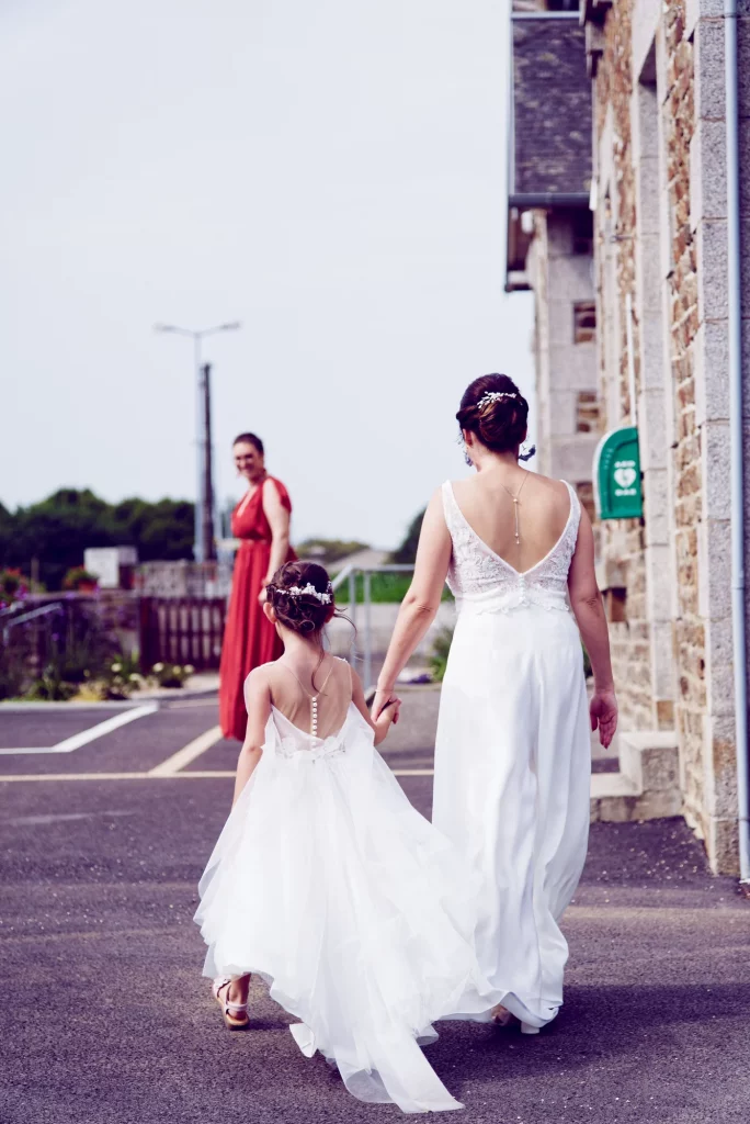 Mariée et demoiselle d'honneur marchant main dans la main à Saint-Hilaire-du-Harcouët en Normandie.