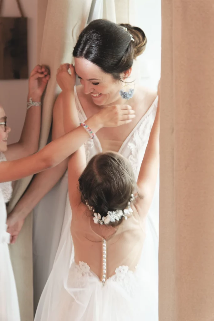 Mariée souriante aidée par ses demoiselles d'honneur lors des préparatifs de mariage en Normandie.