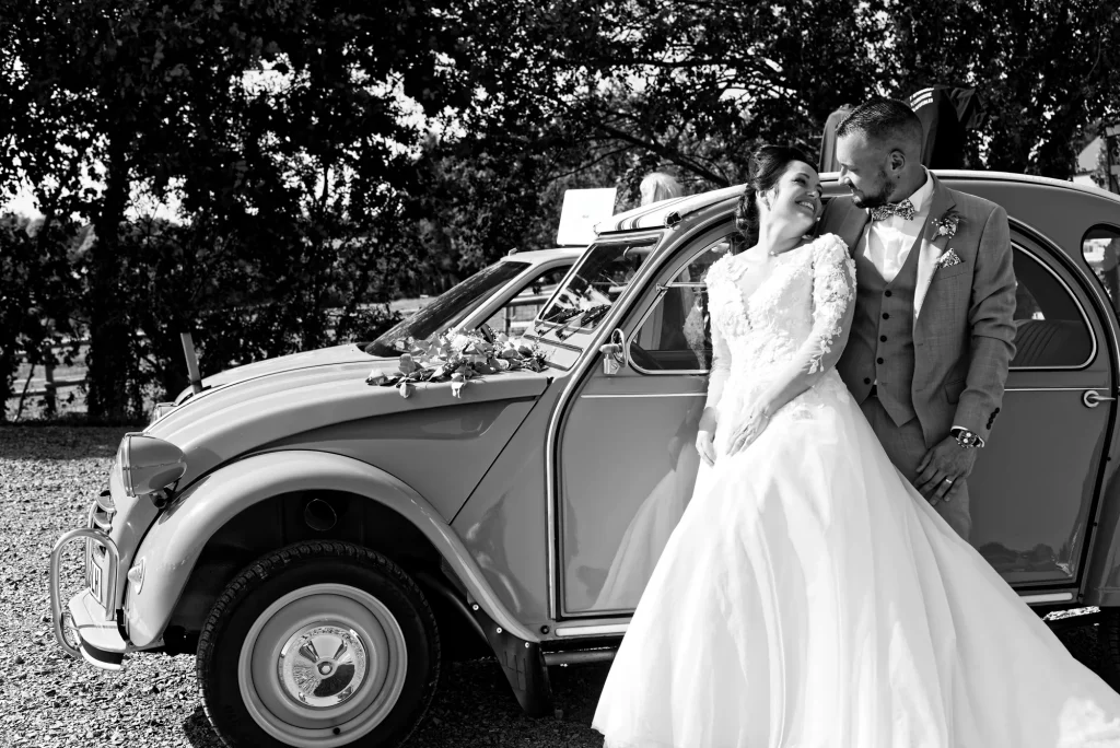 Les mariés posant avec élégance devant une Citroën 2CV vintage pour un style bohème chic.