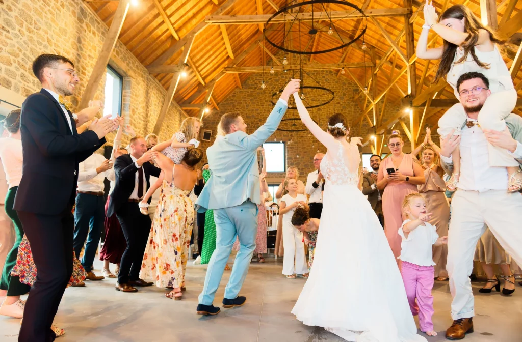 Mariés dansant à Saint-Hilaire-du-Harcouët, invités en liesse dans une grange normande.