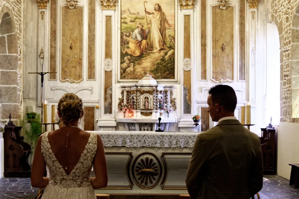 Mariés de dos devant l'autel lors d'une cérémonie de mariage à Saint-Hilaire-du-Harcouët, Normandie.
