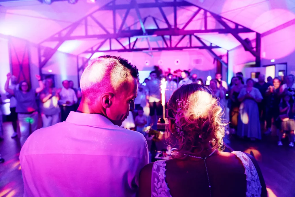 Mariés de dos face à la piste de danse illuminée en violet, mariage à Saint-Hilaire-du-Harcouët.