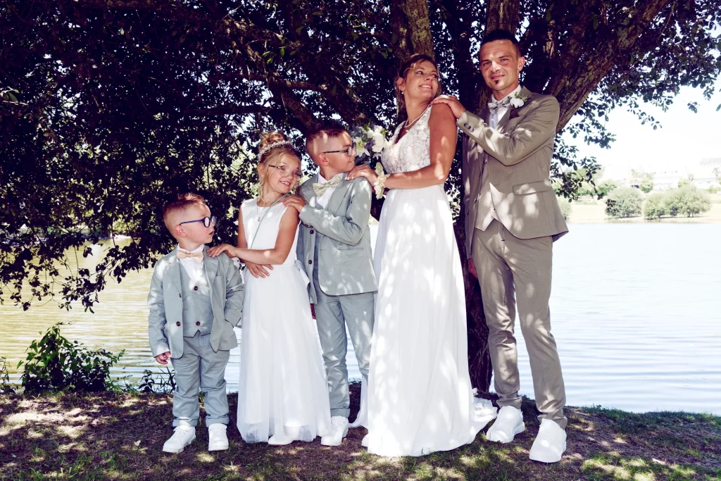 Mariés et leurs trois enfants posent sous un arbre au bord d'un lac à Saint-Hilaire-du-Harcouët, Normandie.