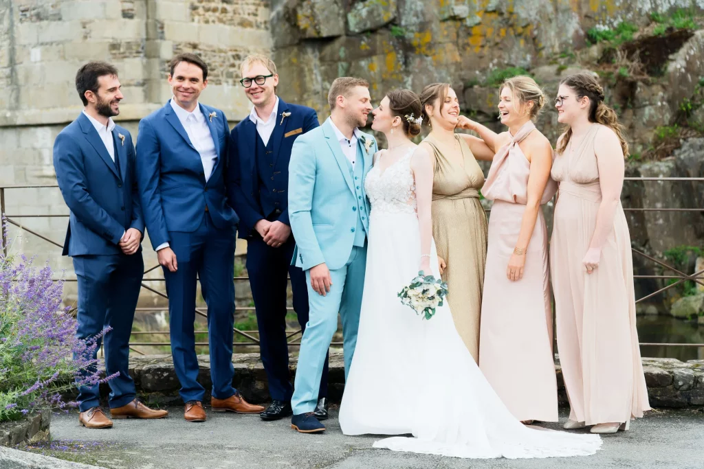 Mariés et témoins devant un mur de pierre à Saint-Hilaire-du-Harcouët en Normandie.