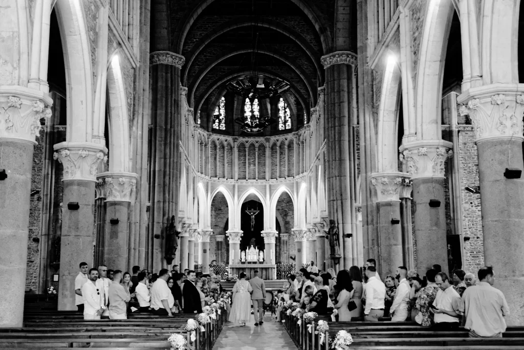 Mariés marchant vers l'autel d'une église à Saint-Hilaire-du-Harcouët, Normandie. Photo noir et blanc documentaire.