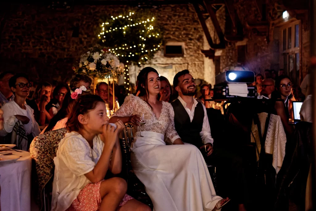 Mariés riant devant une projection nocturne lors d'un mariage à Saint-Hilaire-du-Harcouët en Normandie.