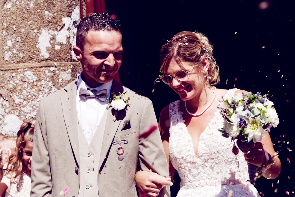 Mariés souriants sous une pluie de pétales à Saint-Hilaire-du-Harcouët, Normandie.