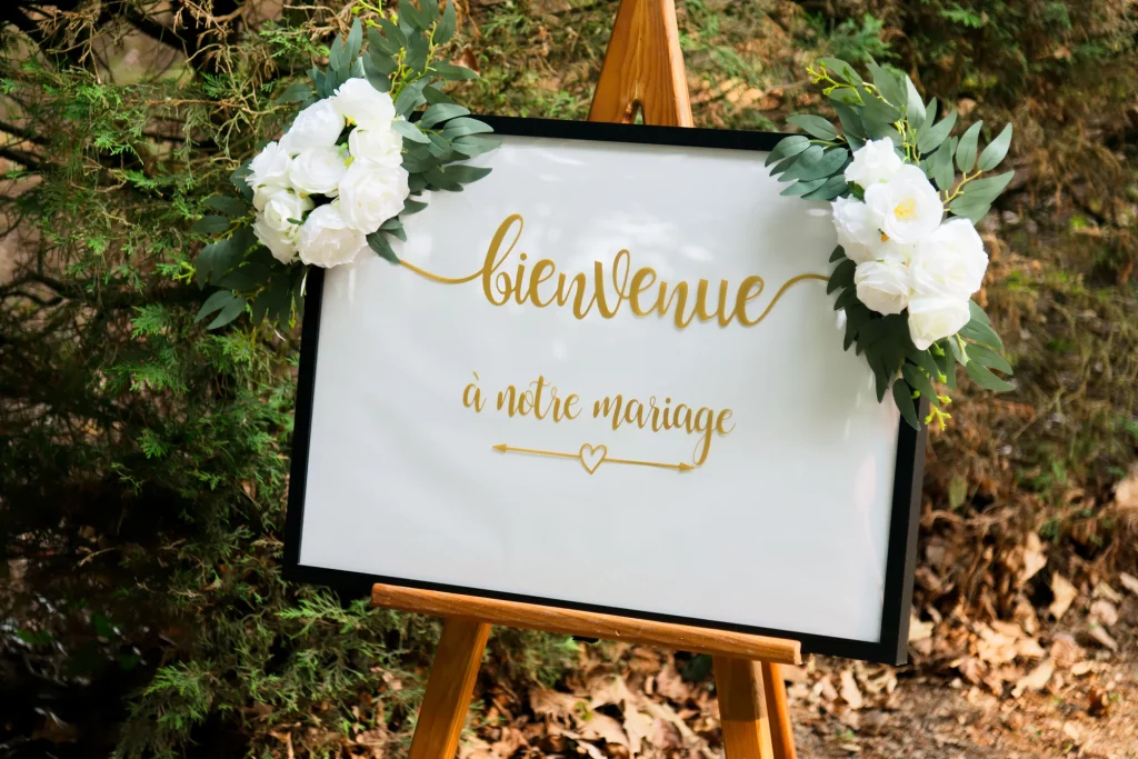 Panneau de bienvenue mariage en Normandie avec roses blanches et eucalyptus sur chevalet en bois.