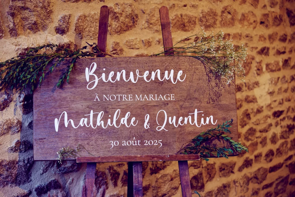 Panneau en bois de bienvenue pour le mariage de Mathilde et Quentin en Normandie décoré de fleurs.