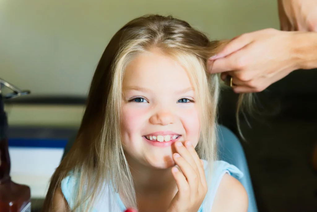 Petite fille blonde souriante se faisant coiffer pour un mariage à Saint-Hilaire-du-Harcouët, Normandie.