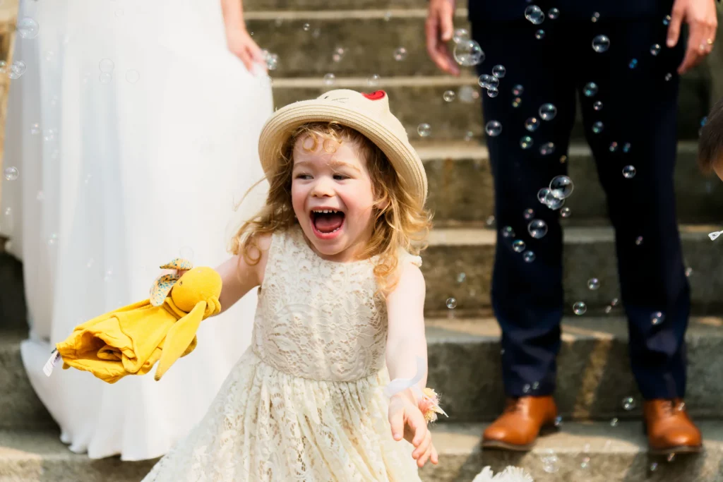 Petite fille rit sous des bulles lors d'un mariage à Saint-Hilaire-du-Harcouët, Normandie.