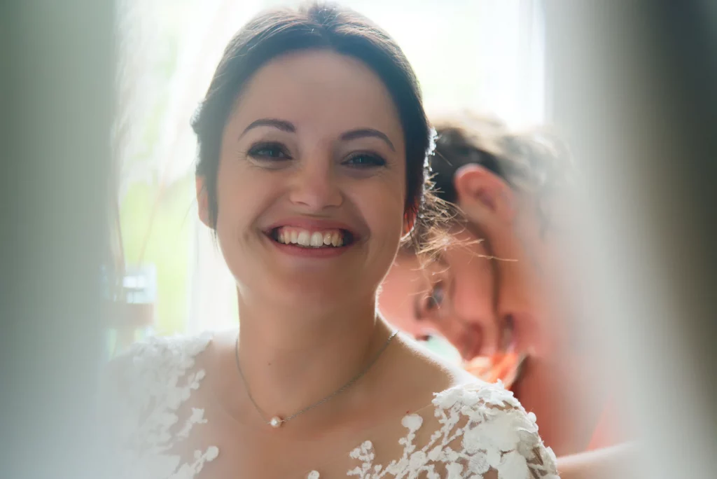 Portrait d'une mariée souriante en robe de dentelle blanche à Saint-Hilaire-du-Harcouët, Normandie.
