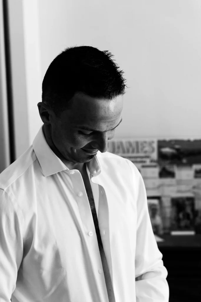 Portrait noir et blanc d'un marié ajustant sa chemise à Saint-Hilaire-du-Harcouët, Normandie.