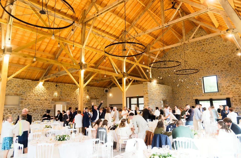 Réception de mariage dans une grange à Saint-Hilaire-du-Harcouët, Normandie, avec grands lustres circulaires.