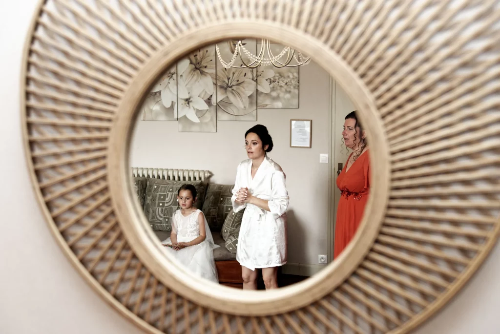 Reflet miroir rotin : mariée en peignoir blanc et fillette à Saint-Hilaire-du-Harcouët, Normandie.