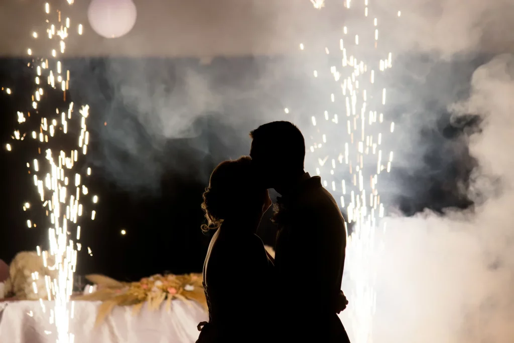 Silhouette d'un couple marié s'embrassant au milieu de gerbes d'étincelles et fumée en Normandie.