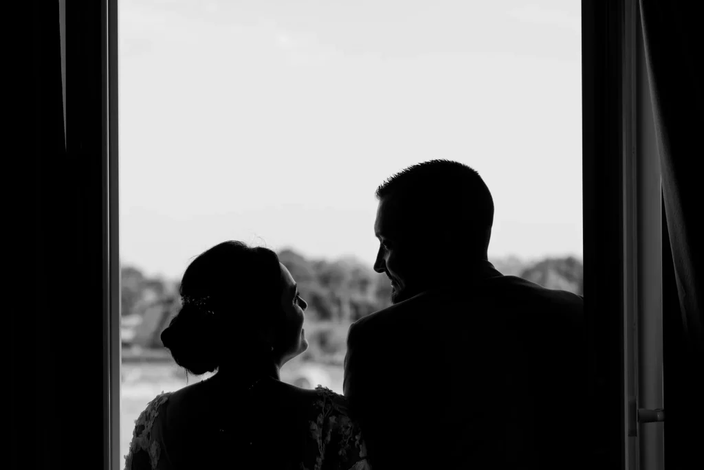 Silhouette en clair-obscur de Maëva et Valentin se regardant à travers une fenêtre.