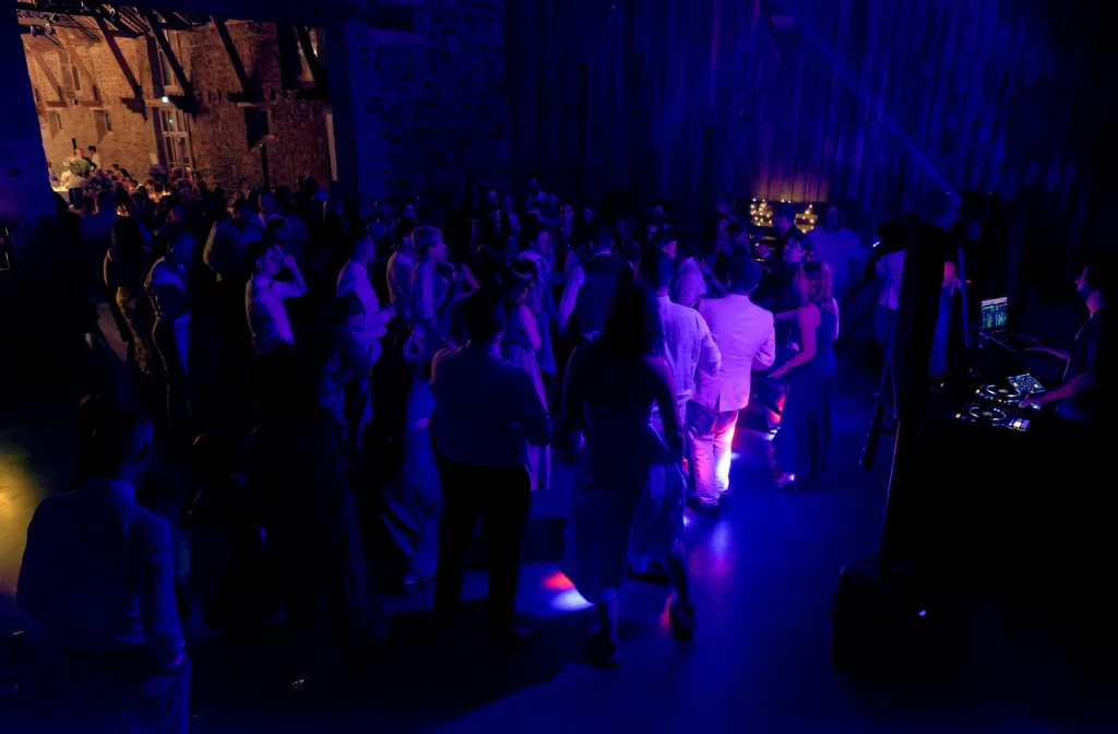 Soirée de mariage en Normandie à Saint-Hilaire-du-Harcouët, invités dansant sous des projecteurs bleus.