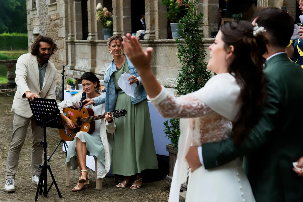 Une femme joue de la guitare et chante pour les mariés lors d'une cérémonie en plein air en Normandie.