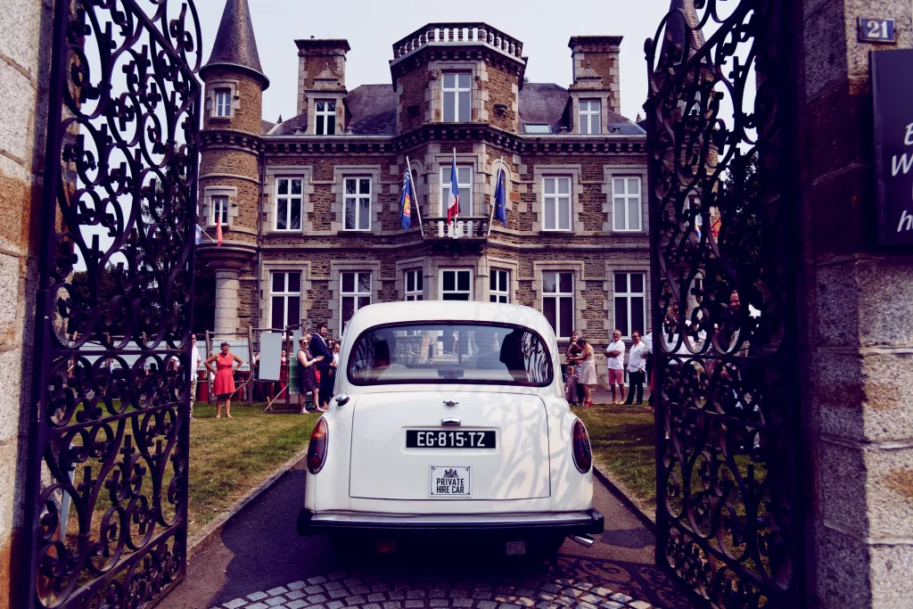 Voiture vintage blanche devant un château de Normandie lors d'un mariage à Saint-Hilaire-du-Harcouët.